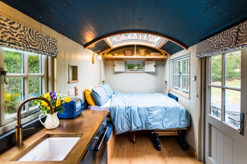 a small bedroom with a bed and a sink at Nutkins Luxury Shepherd Hut with hot tub close to Lyme Regis in Uplyme