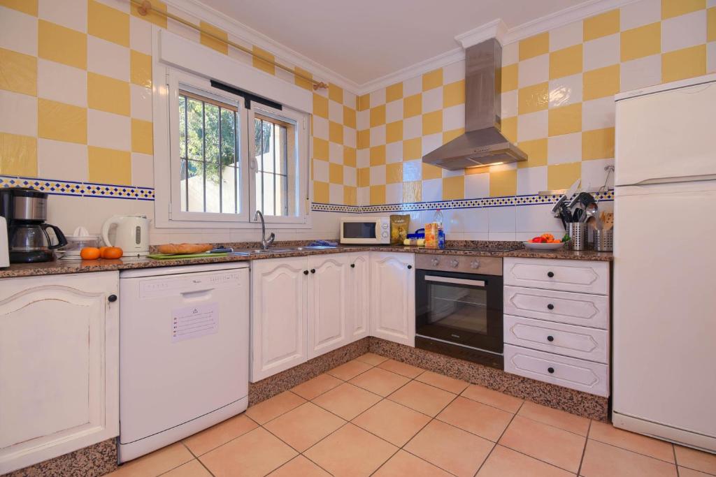 a kitchen with white appliances and yellow tiled walls at Monte Rosa in Jávea