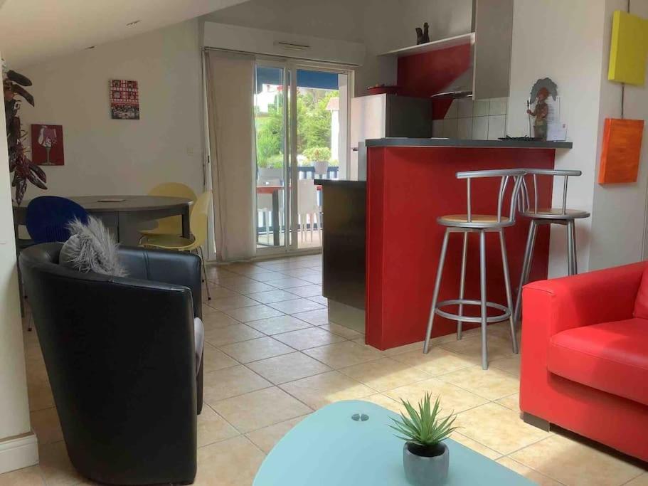 a kitchen and a living room with a red counter top at Bidart côte basque T3 250 mètres de la plage 3*** in Bidart