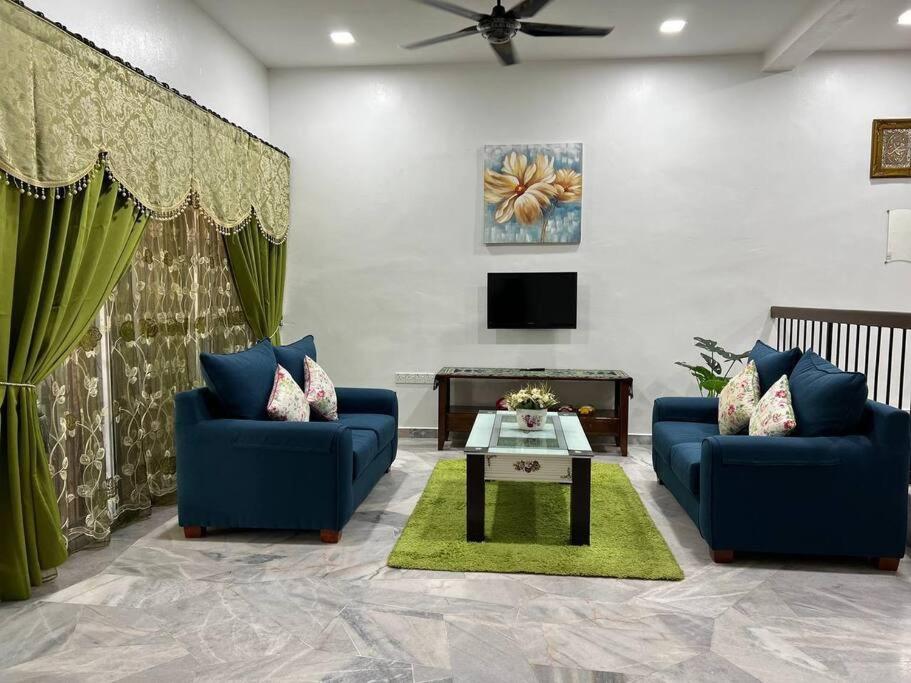 a living room with two blue couches and a tv at One's Homestay in Seri Manjung