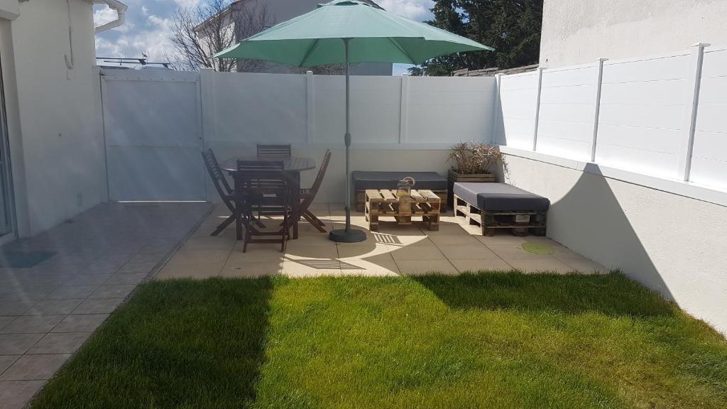 a patio with a table and a green umbrella at '' FLEUR DE SEL '' in Saint-Hilaire-de-Riez