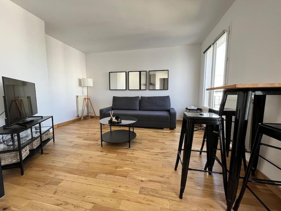 un salon avec un canapé bleu et un parquet dans l'établissement Appartement Emplacement Idéal de Disney à Paris, à Serris