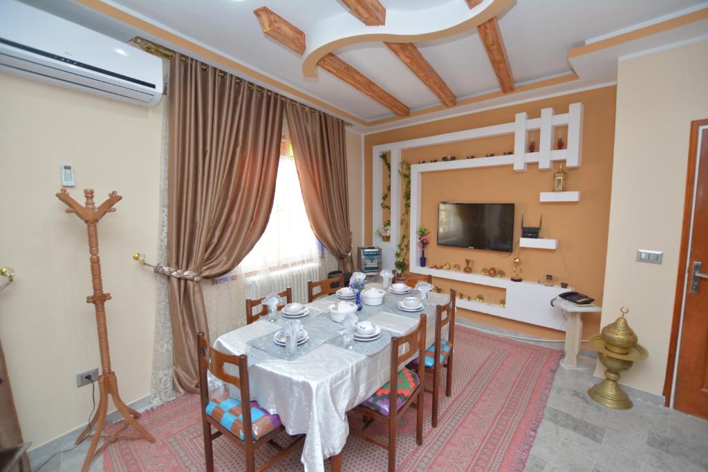 una sala da pranzo con tavolo, sedie e TV di Maison D'hôte Dar Saida a Sicca Veneria