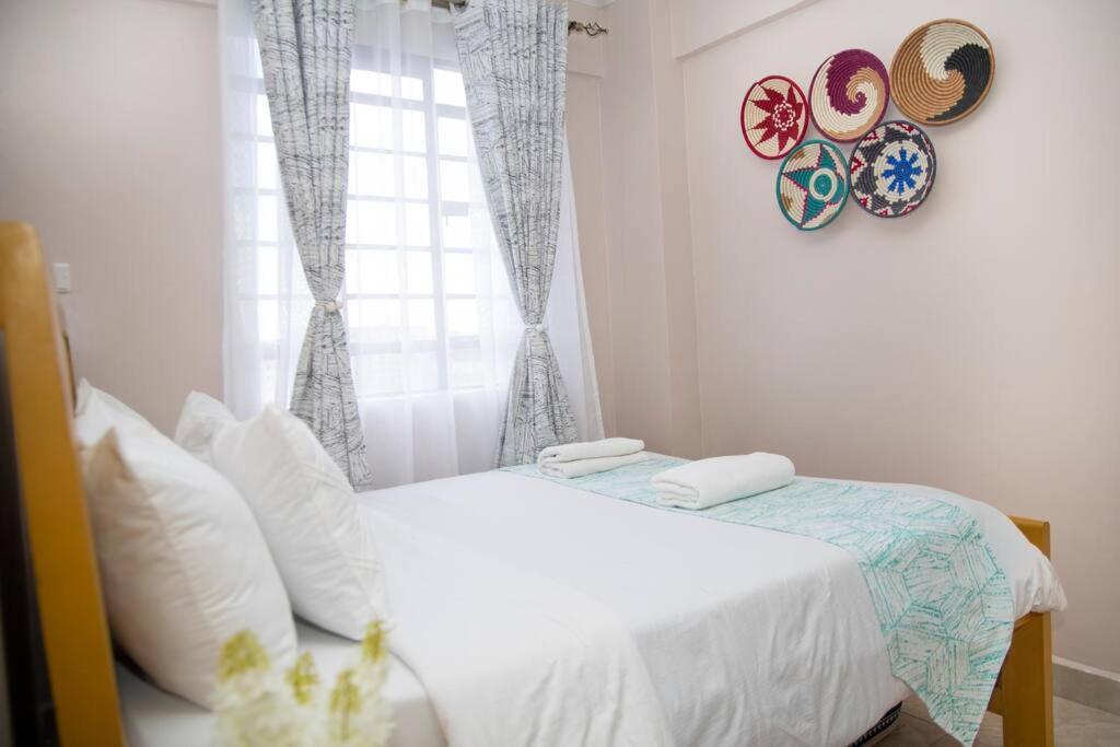 Habitación blanca con cama y ventana en Lovely 1-bedroom apartment with free parking, en Nairobi