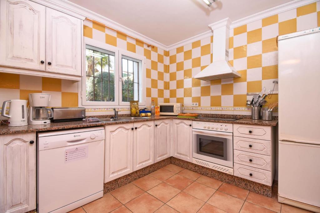 a kitchen with white cabinets and yellow tiles at Monte Violeta in Jávea