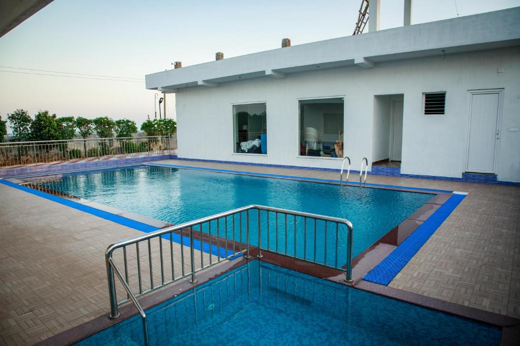 a swimming pool in front of a house at Thai Beach Resort in Thiruchendur