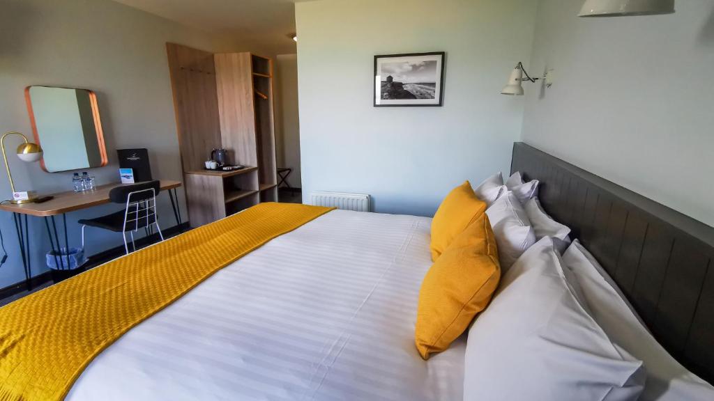 a bedroom with a large bed with yellow and white pillows at Marine Hotel Ballycastle in Ballycastle