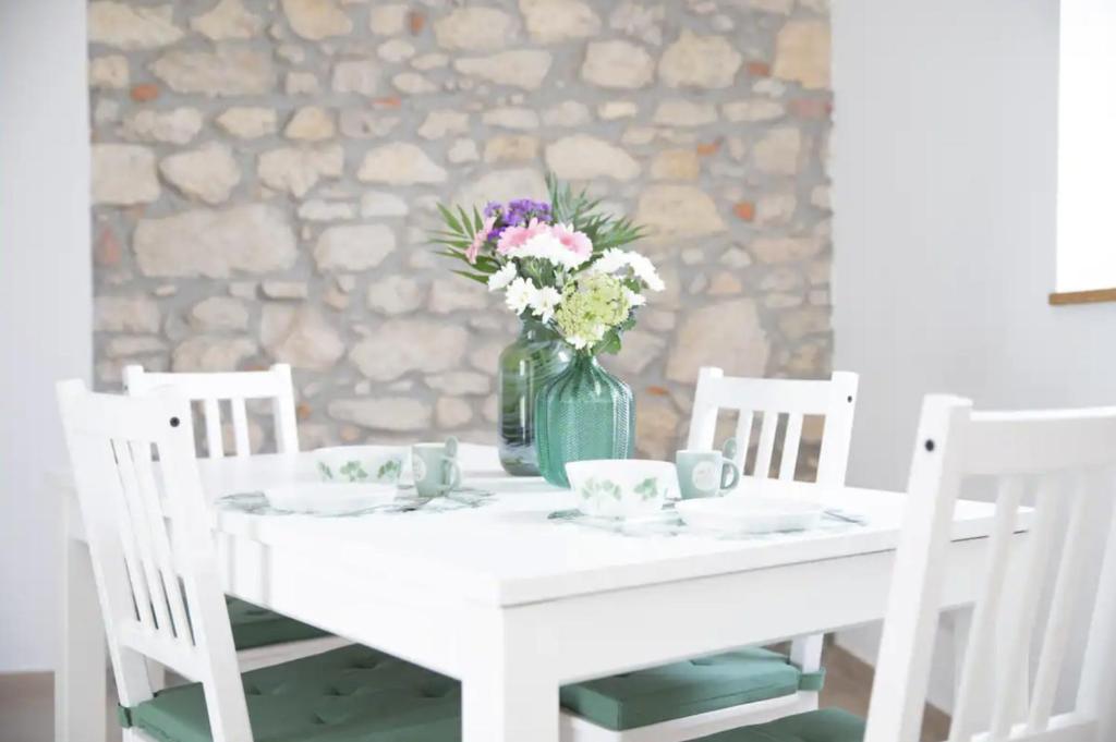 Una mesa blanca con un jarrón de flores. en Casa Dolce Casa _ a due passi dal Lago Maggiore, en Angera