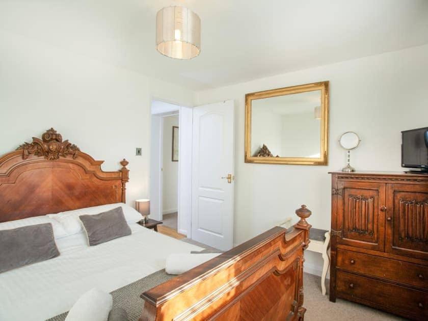 a bedroom with a large wooden bed and a mirror at Waterside Park Annex in Kingsbridge