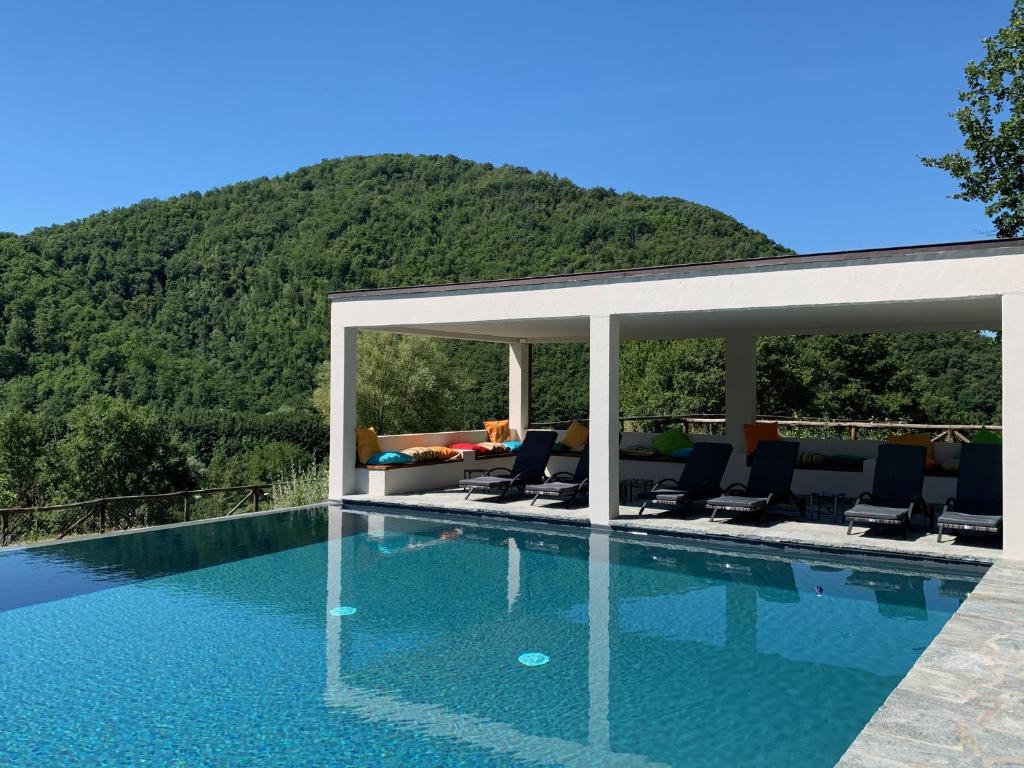a swimming pool with chairs and a mountain in the background at Estia - In Parulia Country House in Arezzo