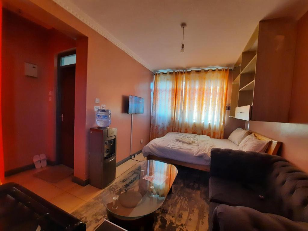 a small room with a bed and a couch at Pine Residency w Secure Parking, Wifi, Netflix & Rooftop Views in Kikuyu