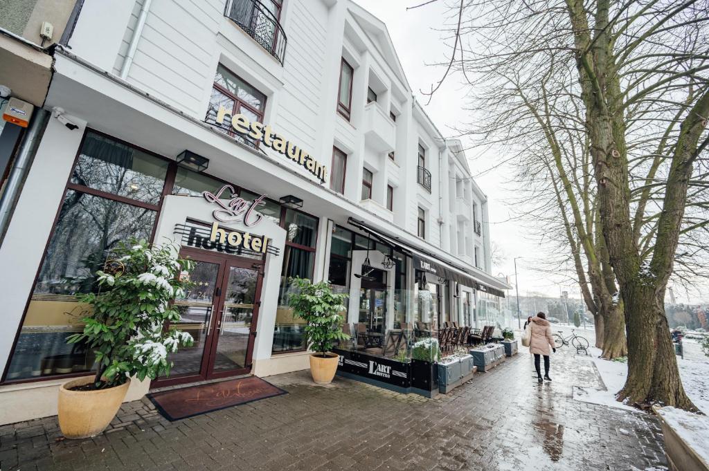 una mujer caminando por una acera delante de una tienda en L`Art Hotel Carei, en Carei