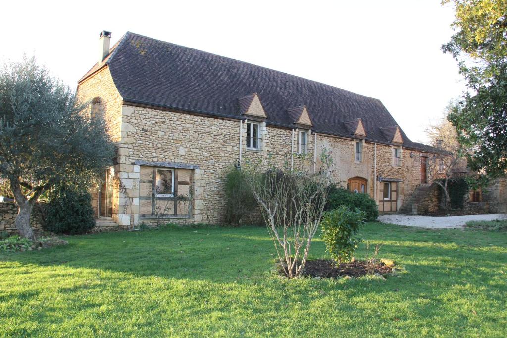 ein großes Backsteingebäude mit einem Rasenplatz in der Unterkunft Manoir de La Brunie-Grand Longere in Coux-et-Bigaroque