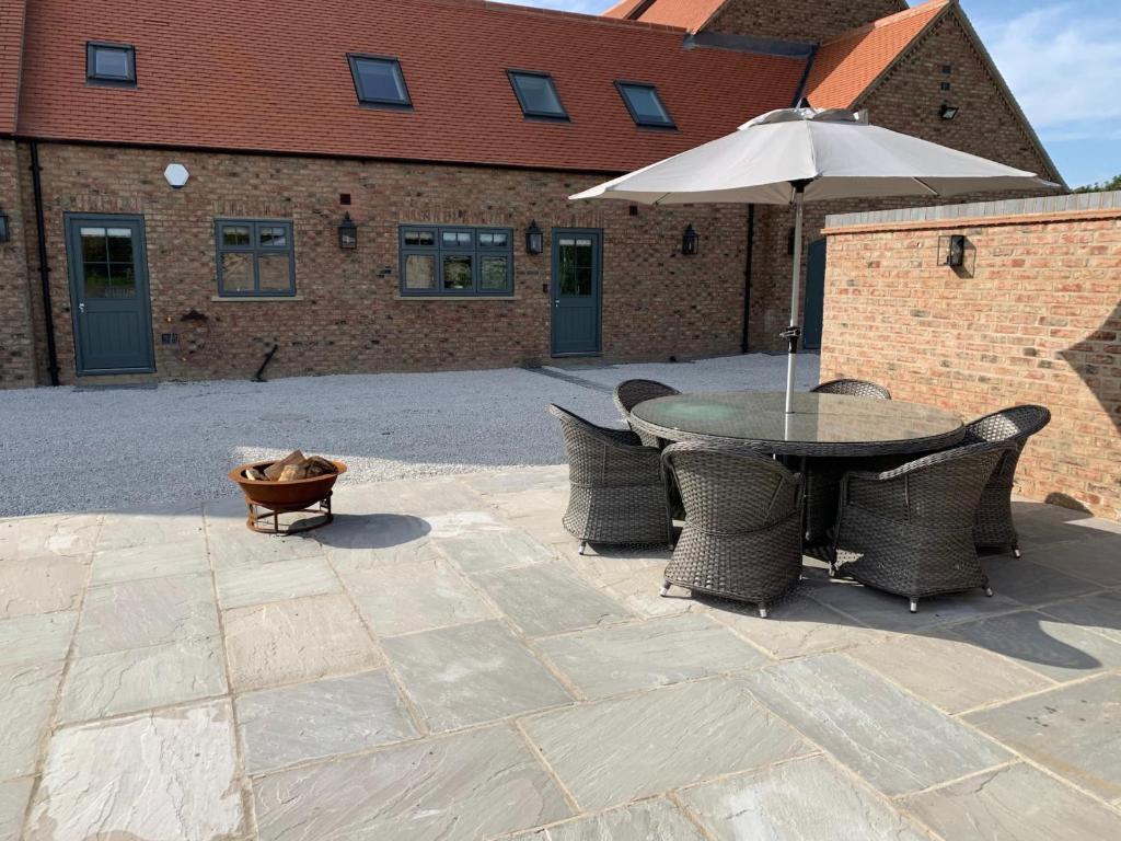 a patio with a table and chairs and an umbrella at Luxury Boutique Country Cottage with Hot Tub in York