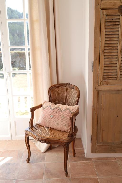 a wicker chair with a pink pillow in a room at Le Clos Serein in Le Beausset