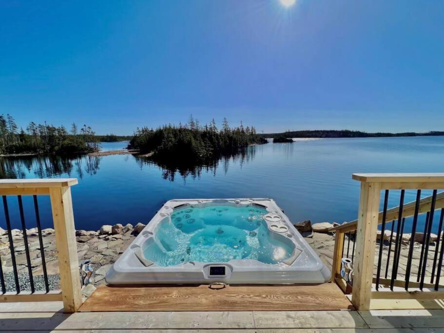 a hot tub on a deck next to a body of water at Sable Point Cottage (Lakeside 7-Person Hot Tub & Outdoor Shower) in Grand River