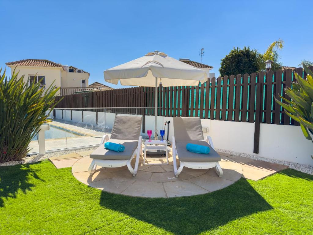 a patio with two chairs and a table with an umbrella at Ayia Napa Holiday Villa 040 in Ayia Napa