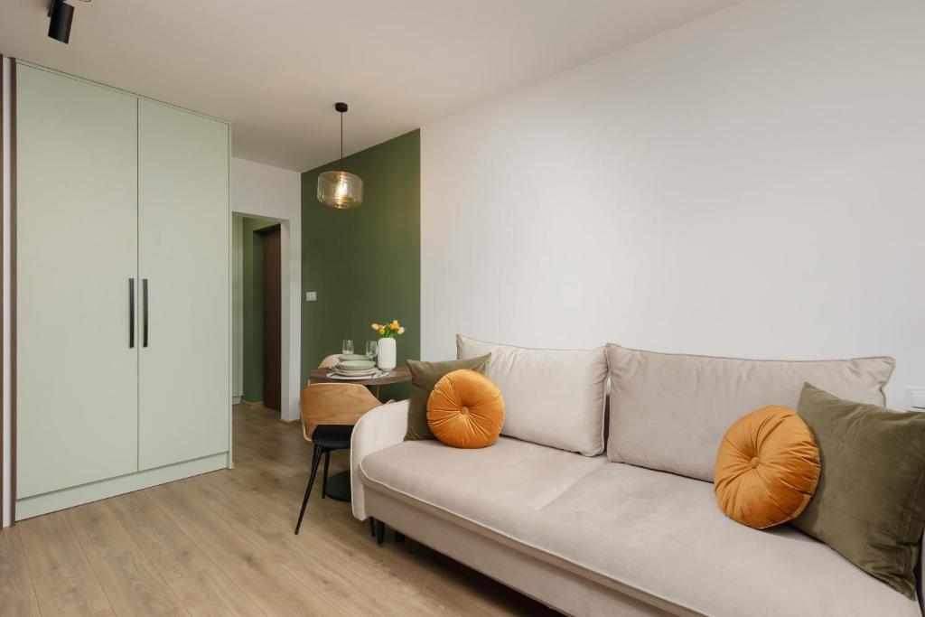 salon z białą kanapą z pomarańczowymi poduszkami w obiekcie Cozy Studio Apartment Kolorowa Warsaw Ursus by Renters w Warszawie