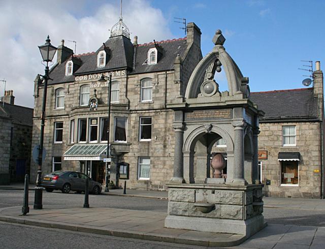 a stone building with a statue in front of it at The Gordon Arms Hotel in Huntly