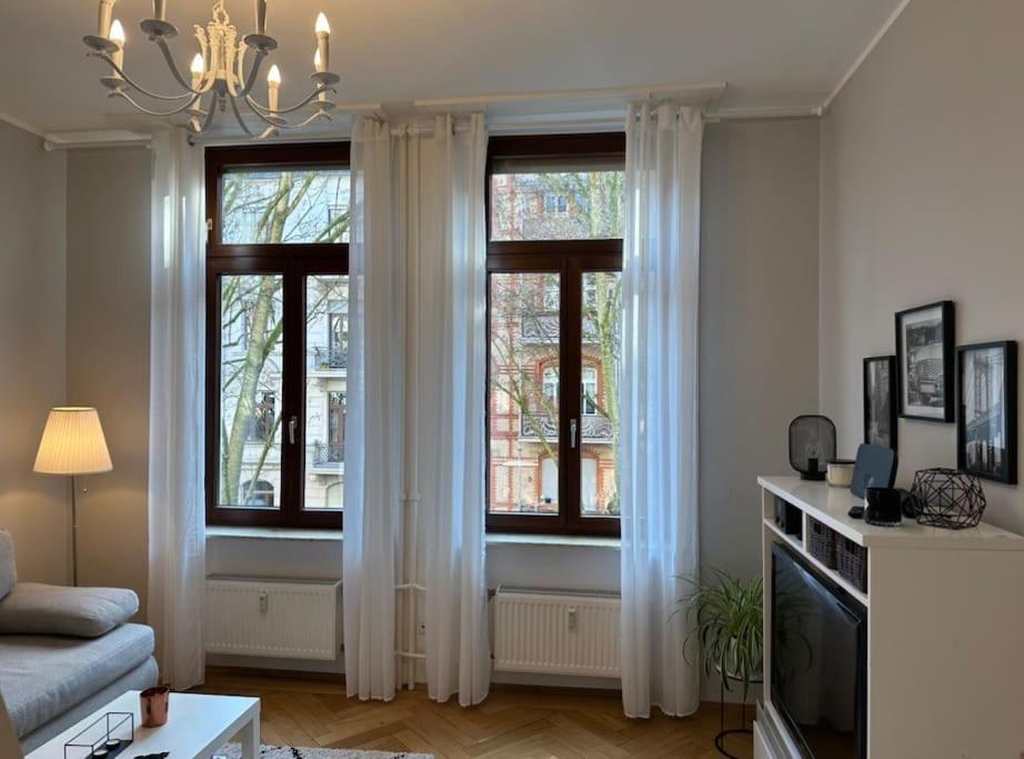 un soggiorno con 2 finestre e tende bianche di APT im Herzen von Wiesbaden a Wiesbaden
