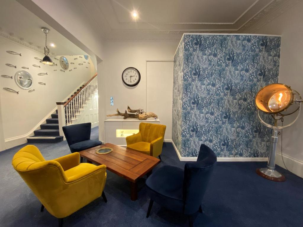 uma sala de estar com cadeiras amarelas e uma mesa em Rooms At Babbacombe em Torquay