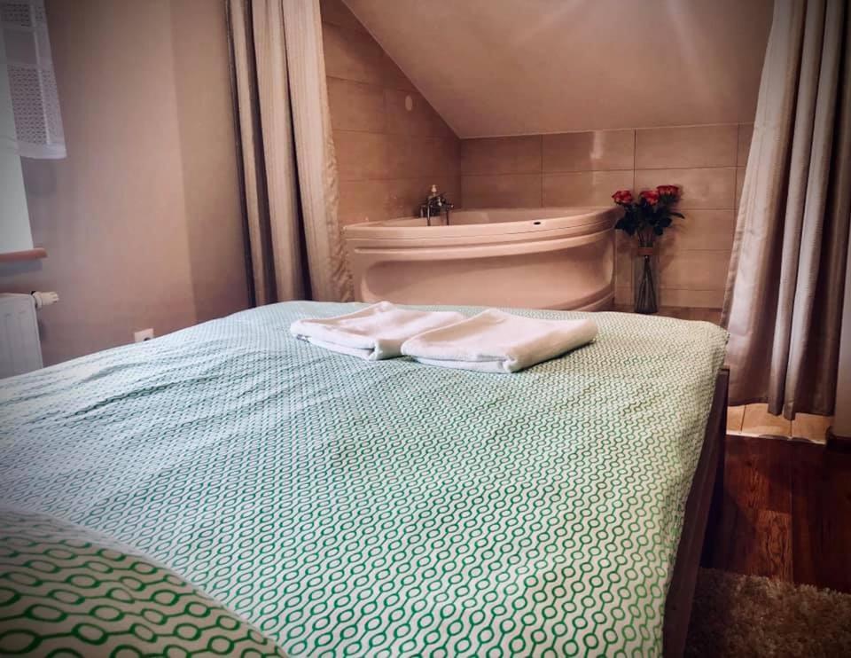 1 cama con 2 toallas y bañera en Piątka noclegi- Łódź en Lodz
