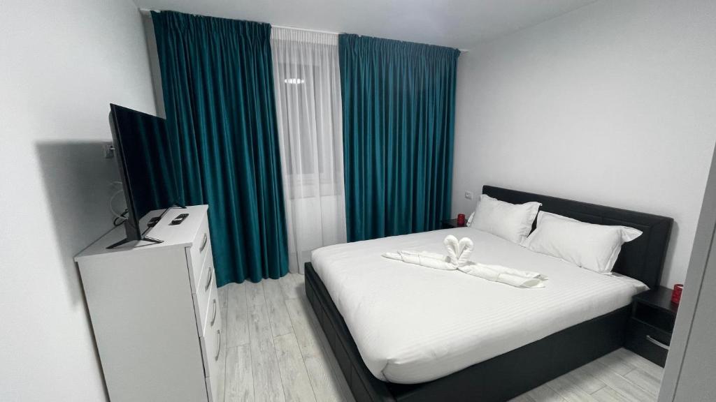 um quarto com uma cama branca e cortinas verdes em APARTAMENT 2 CAMERE CENTRU ONESTI em Onesti