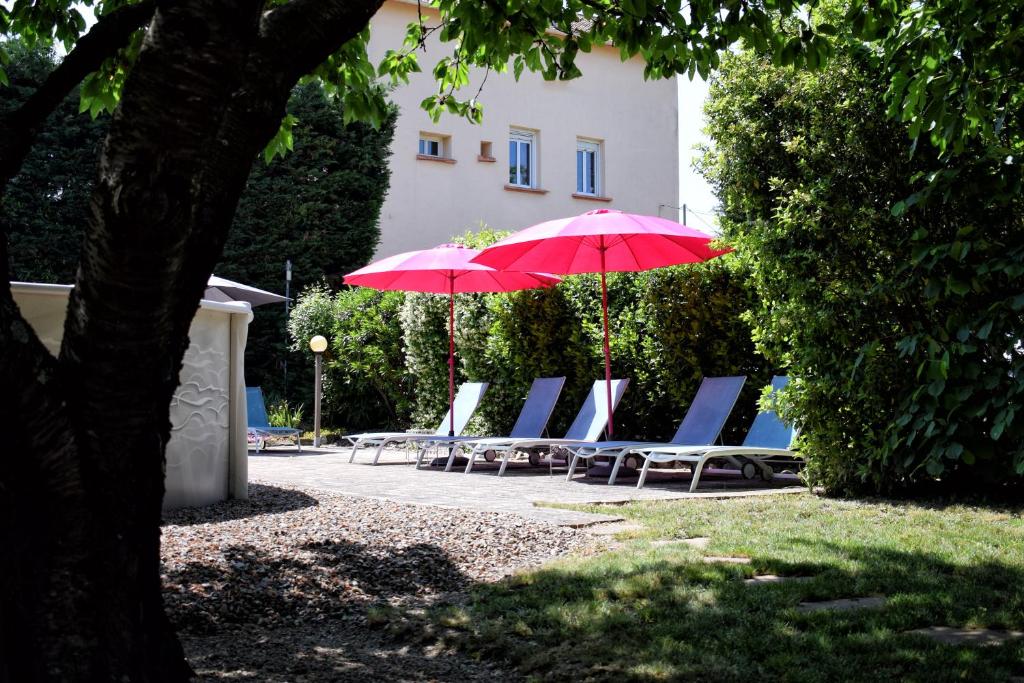 a group of lounge chairs and red umbrellas at L'Oustaloise in Faugères