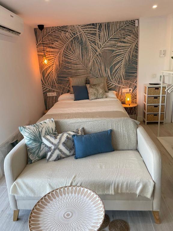 a bedroom with a bed and a couch with a mural at Apartamento Tres Banderas in Estepona