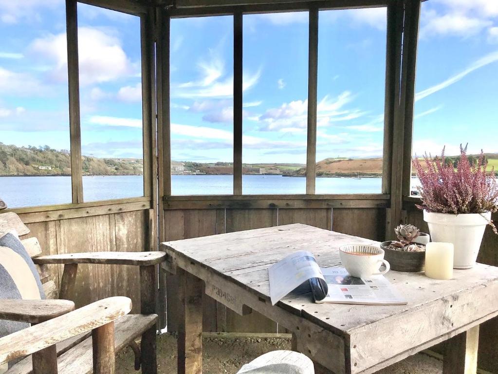 a wooden table and chairs with a view of a lake at Coastal Chic waterfront studio in Kinsale