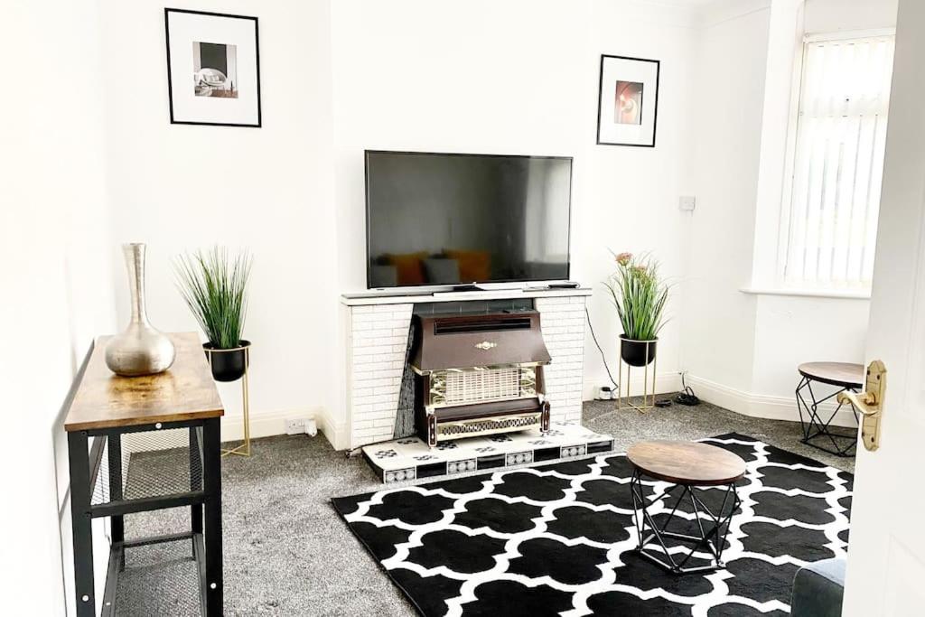 een woonkamer met een televisie en een zwart-wit tapijt bij Rochester Townhouse with parking in Strood