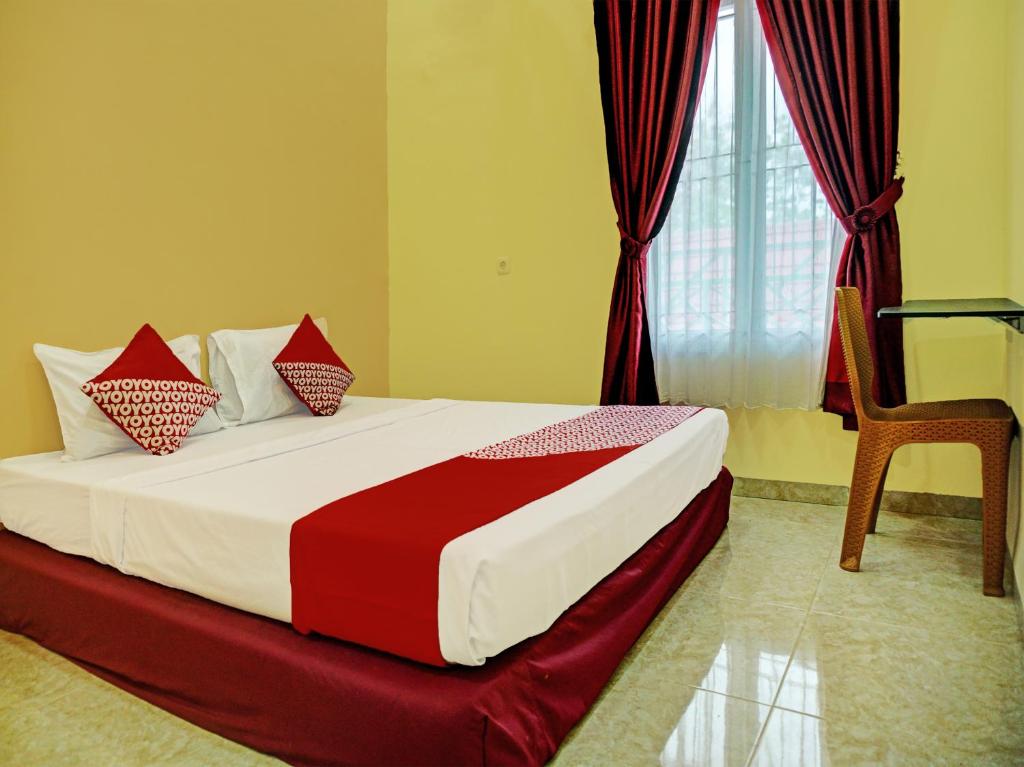 a bedroom with a large bed with a window and a chair at OYO 92293 Pahala Syariah Residence in Prabumulih