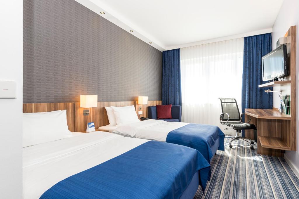 ein Hotelzimmer mit 2 Betten und einem TV in der Unterkunft Holiday Inn Express Bremen Airport, an IHG Hotel in Bremen