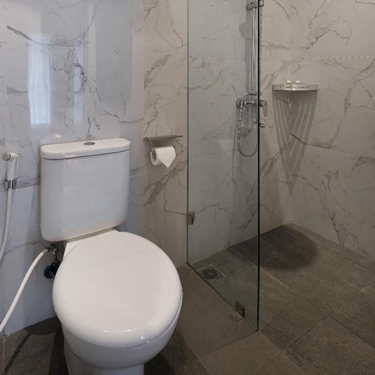 een badkamer met een toilet en een glazen douche bij The Risman Hotel At Jakarta Airport CBC in Tangerang