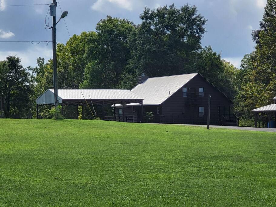 a black barn with a white roof in a field at 8. Beautiful secluded creek front lodge in Guntersville