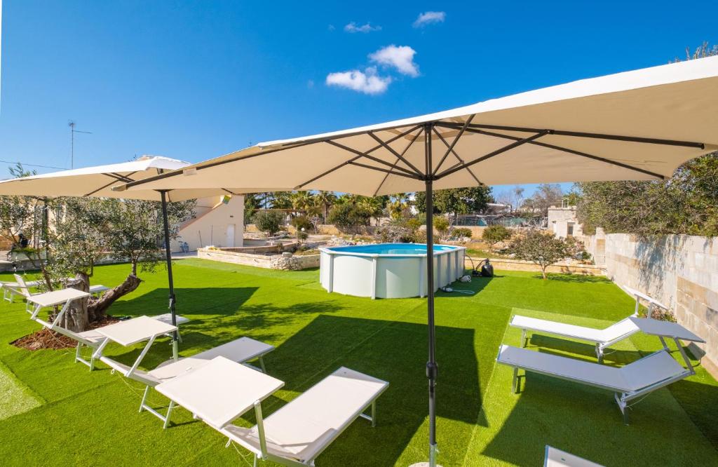 a patio with an umbrella and chairs and a pool at Villa Lusia con Piscina Privata a Pescoluse in Marina di Pescoluse