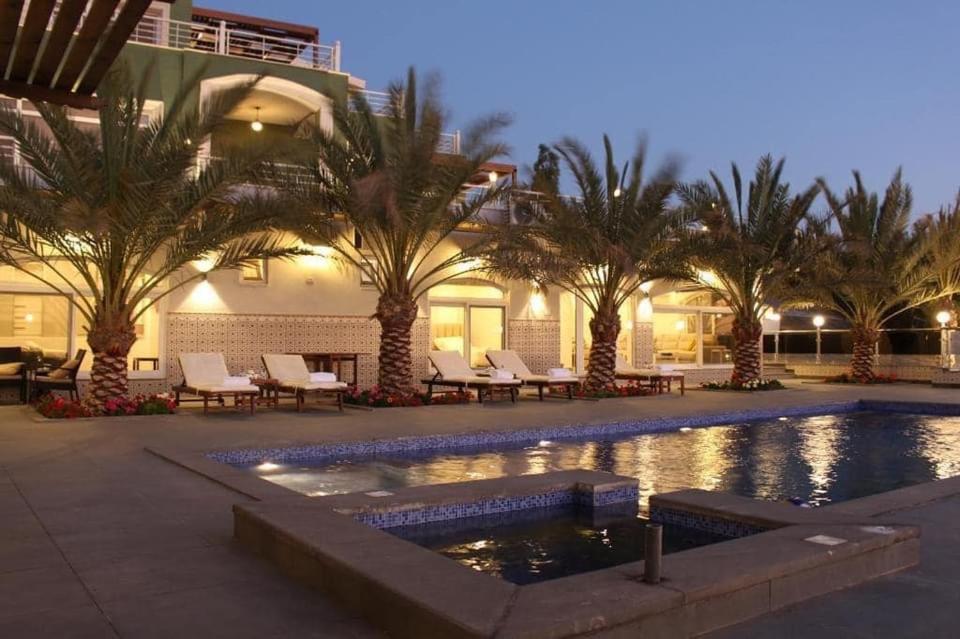 a resort with a pool and palm trees at night at Golden rays chalet in Madaba