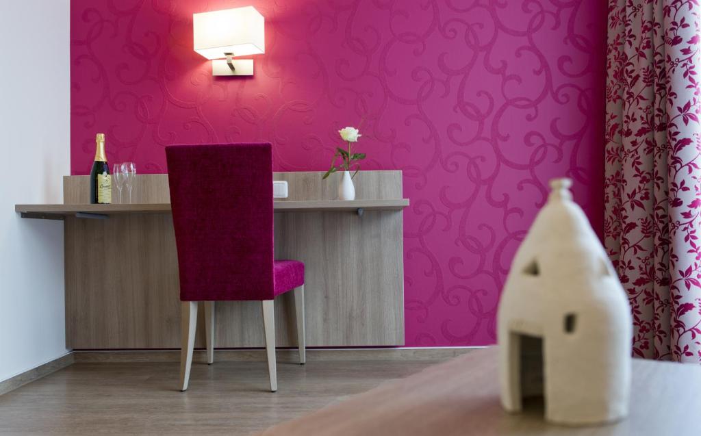 um quarto rosa com uma mesa e uma cadeira roxa em Landhotel im Klostereck Strubel-Roos em Flonheim