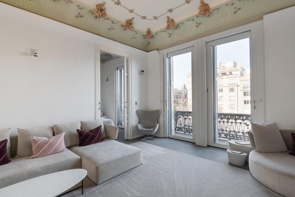 a living room with a couch and some windows at El Palauet Royal Suites in Barcelona