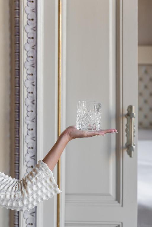 a person holding a glass in front of a door at El Palauet Royal Suites in Barcelona