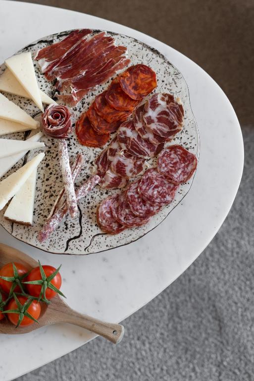 a plate of meat and cheese on a table at El Palauet Royal Suites in Barcelona
