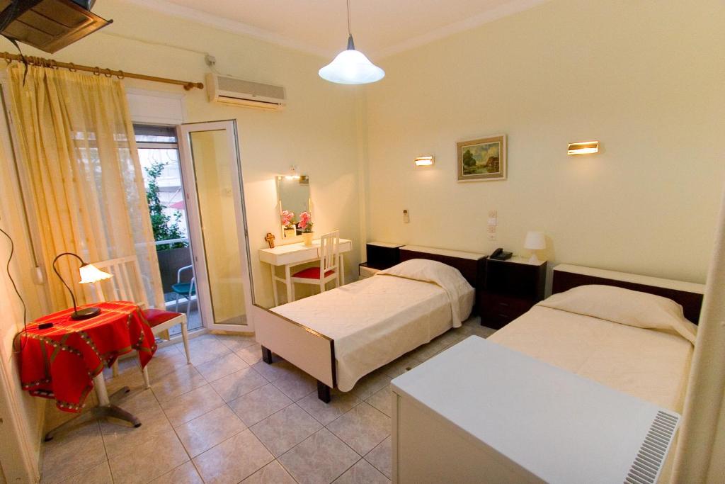 a bedroom with two beds and a desk and a table at ΩΚΕΑΝΙΣ in Loutra Edipsou