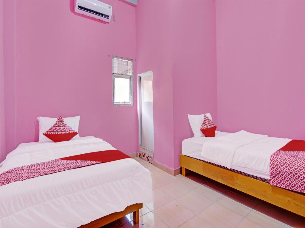 Bangkinang的住宿－OYO 92302 Salsa Homestay Syariah，配有粉红色墙壁的客房内的两张床