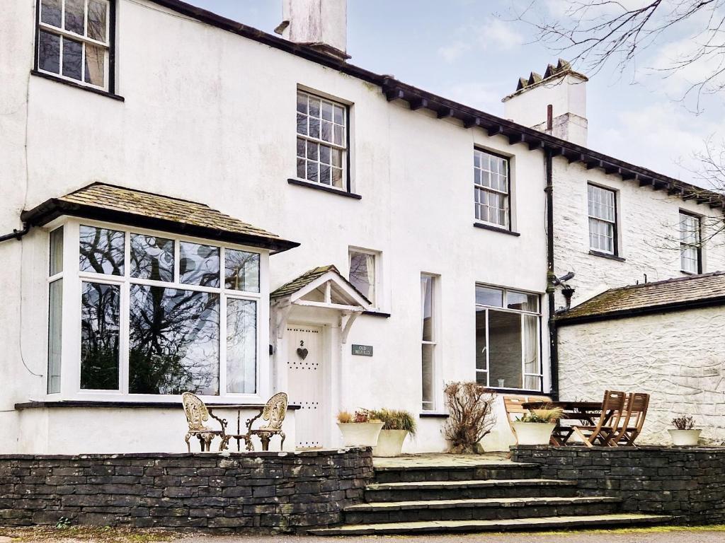 a white house with chairs in front of it at Old Belfield in Bowness-on-Windermere