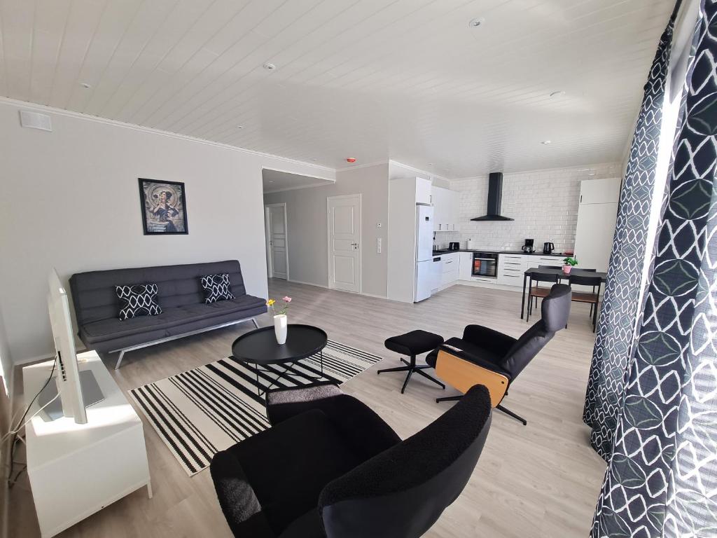 ein Wohnzimmer mit schwarzen Möbeln und eine Küche in der Unterkunft ALEX - bright, stylish apartment with sauna, built in 2023 in Närpiö