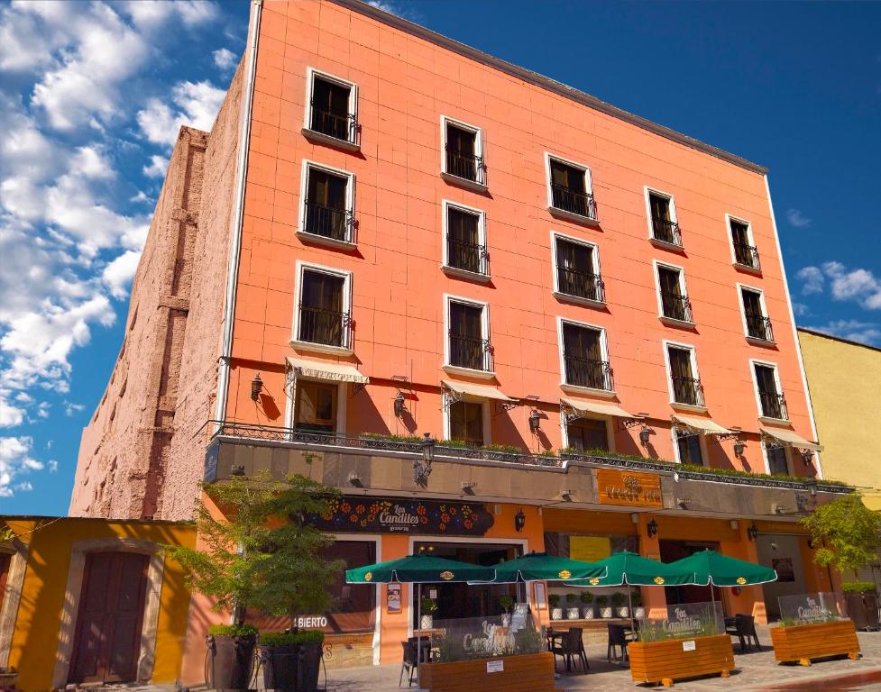 un gran edificio naranja con sombrillas verdes delante de él en HOTEL LAGOS INN, en Lagos de Moreno