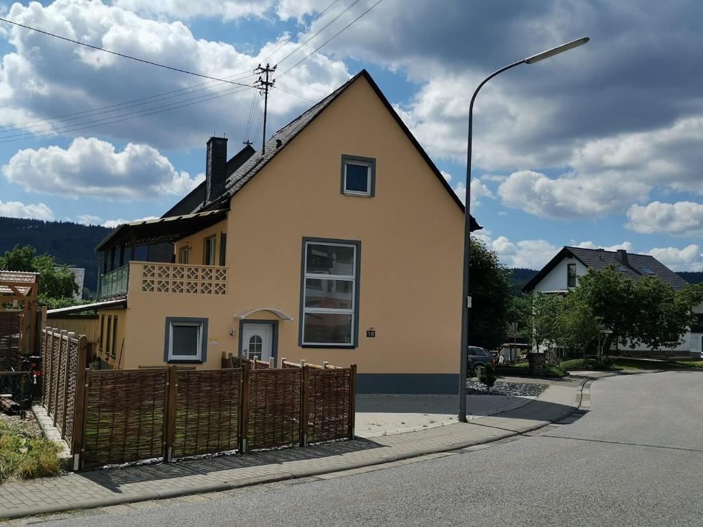 ein gelbes Haus mit einem Zaun und einem Straßenlicht in der Unterkunft Ferienhaus Clarissa in Allenbach