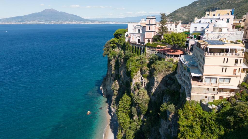 um grupo de edifícios num penhasco junto ao oceano em Hotel Sporting em Vico Equense