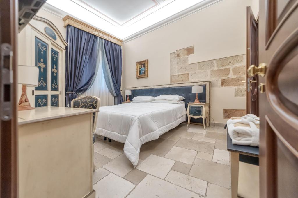 a bedroom with a king sized bed and blue curtains at Kelina Charme Hotel by Cantine Due Palme in Cellino San Marco
