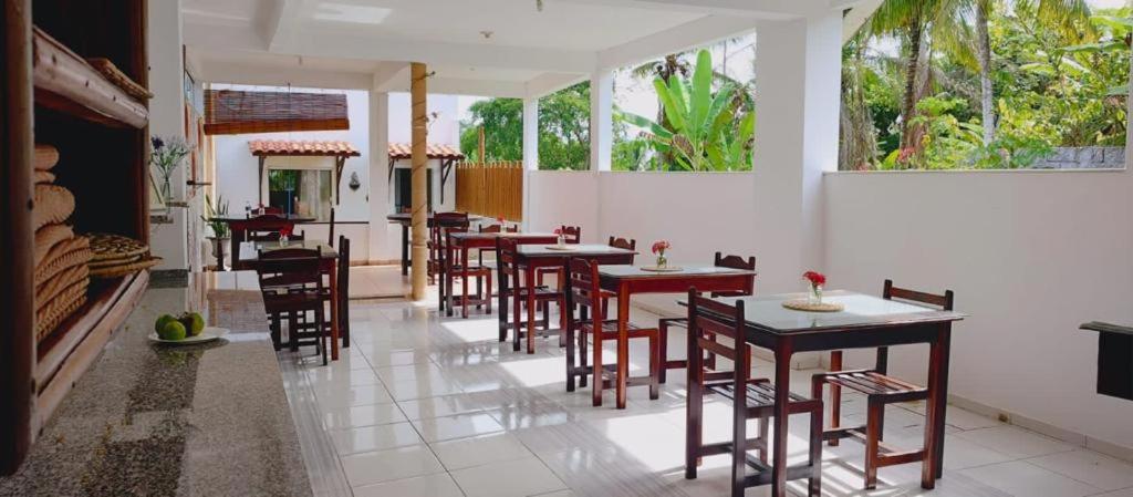 un restaurante con mesas y sillas de madera y ventanas en Estalagem Sol de Boipeba, en Isla de Boipeba